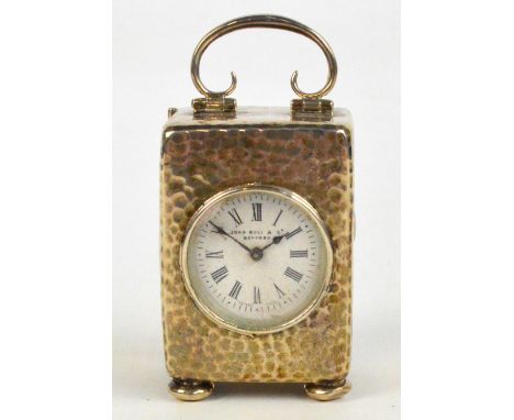 An Edwardian VII hallmarked silver cased small carriage clock with hammered finish and looped handle raised on small bun feet