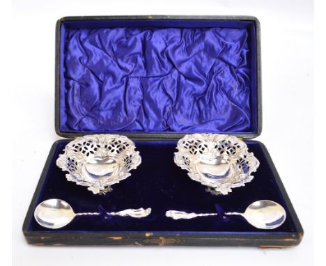 A cased pair of Edward VII hallmarked silver heart shaped dishes with scroll and pierced work decorated sides, on three flora