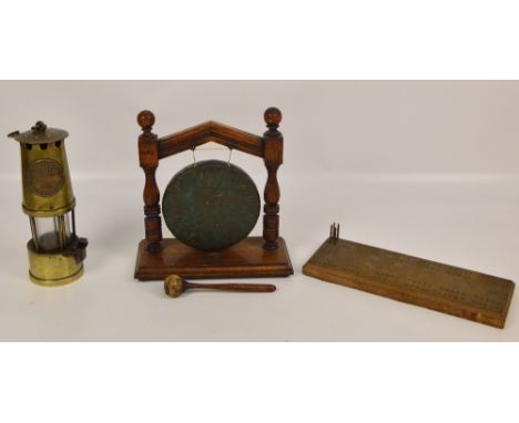 A late 19th century oak framed table gong with striker, diameter 25cm, also a brass miner's lamp and a cribbage board (3).