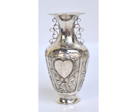 A late 19th/early 20th century Chinese Export silver vase of baluster form, decorated with four floral panels on textured gro