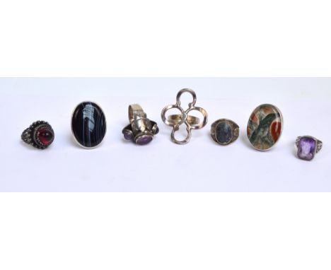 A collection of silver rings including examples set with hardstones, a large floral example, an amethyst example, and an exam