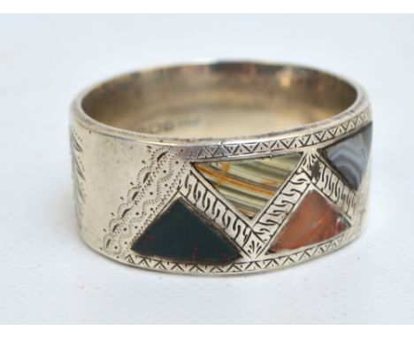 A George V hallmarked silver circular napkin ring with four triangular stone insets including agate, bloodstone and green ony