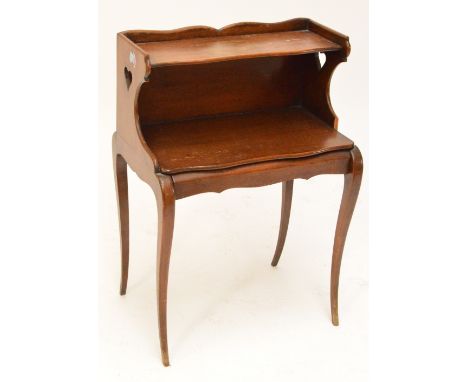 An early 20th century French walnut and stained beech bedside table with shaped shelf above single drawer raised on sabre fro