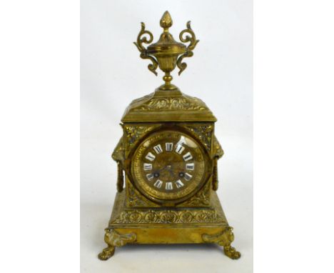A late 19th century French brass mantel clock, the urn finial above circular dial with Roman numerals to shaped enamel plaque