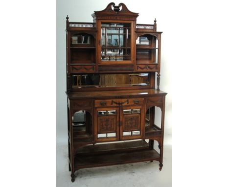 A late Victorian Arts and Crafts walnut display cabinet, the raised back with central glazed door enclosing a mirror, flanked