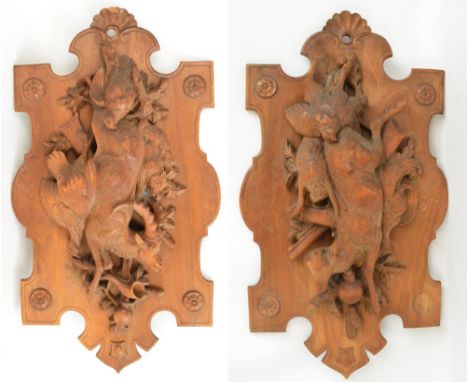 A large pair of early 20th century Black Forest carved walnut and beech plaques, each with detailed carving depicting various