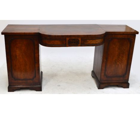 An early 19th century mahogany sideboard with bowfronted central frieze drawer flanked by cupboard doors to a bracket plinth 