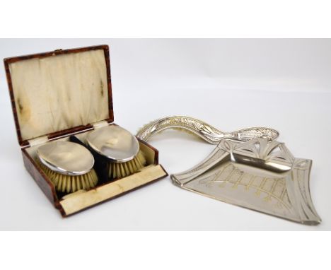 A cased pair of George V hallmarked silver backed brushes with overall engine turned decoration centred with circular vacant 