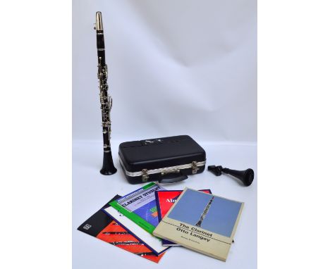 A cased Boosey & Hawkes clarinet plus a small collection of music books and a stand.