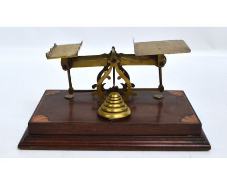 A set of brass Edwardian postal scales with starburst inlaid corners of the wooden rectangular base, with set of six stacking