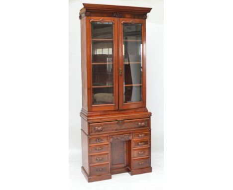 A late 19th century walnut bookcase, the moulded cornice above twin glazed doors enclosing shelves with base centred with a s