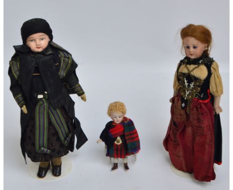 A small early 20th century bisque headed doll with open blue glass eyes, closed mouth and red hair, wearing a gypsy dress, he