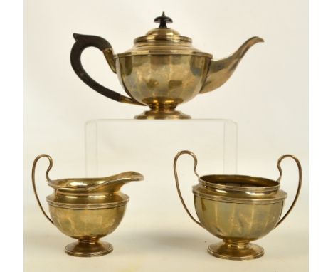 A George V hallmarked silver three piece tea service of circular form with flattened sides, the jug and sugar bowl with loope