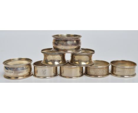 Four pairs of George V hallmarked silver circular napkin rings to include a waisted bead decorated example, Saunders & Shephe