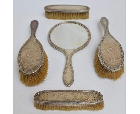 A George V hallmarked silver backed five piece dressing table set comprising a circular hand mirror with overall engine turne