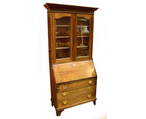 An Edwardian oak bureau bookcase, the moulded cornice above two glazed doors above a base with fall front and three long grad