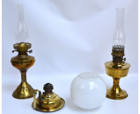 Two early 20th century brass oil lamps with clear glass chimneys, one with opaque globular glass shade, and a further early 2