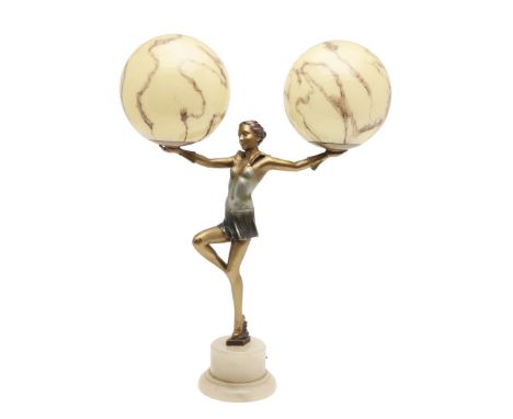 A gilt metal figure of a girl balanced on one leg, with arms outstretched and holding two globular marble effect glass shades