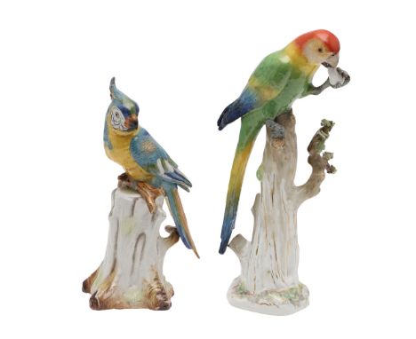 An early 20thc porcelain model of a Parrot perched on a tree stump and holding a piece of fruit, with encrusted decoration an