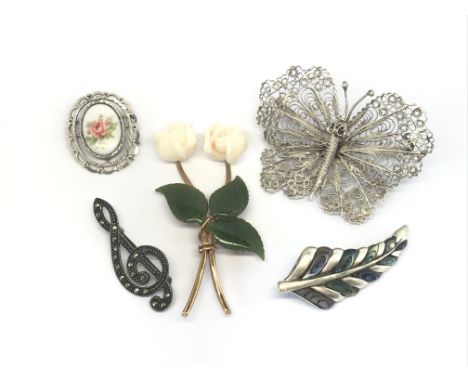 A collection of five brooches including a silver and jade brooch in the form of roses, a filigree brooch of a butterfly, a ma