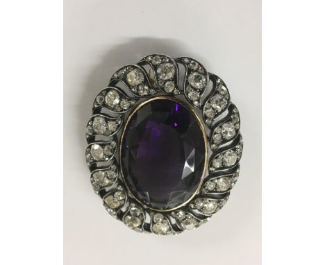 An Fine antique brooch with large central amethyst 50 ct surrounded by a floral style spray of diamonds 8 ct approx total len