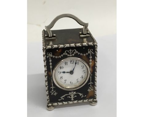 A hallmarked silver mounted tortoiseshell miniature carriage clock with silver pique work decoration. Hallmarks for London 19