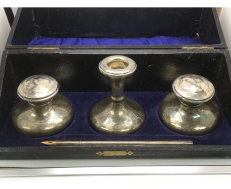 A cased silver writing set comprising a pair of inkwells, candlestick and a pen (pen not originally part of the same set).