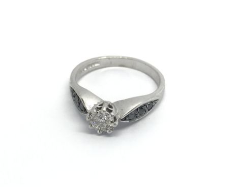 A 9carat white gold ring set a solitaire diamond the shanks set with contrasting black diamonds ring size K