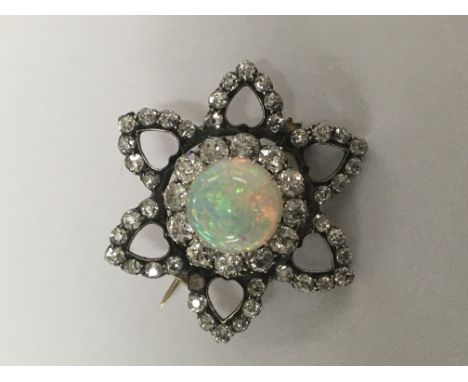 A fine Antique brooch set with central opal surrounded by diamonds of floral form 2 cm .