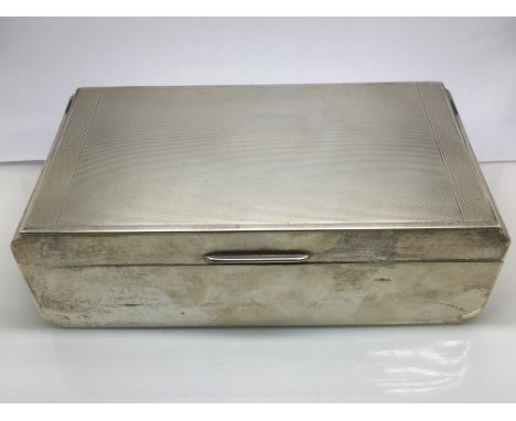 A silver cigar box with engine turned decoration to lid, approx 17cm x 5.5cm x 9cm. London hallmarks.