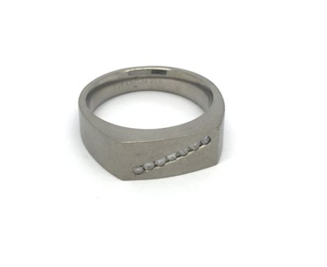 A titanium ring set with seven small diamonds, approx 4.6g and approx size T.