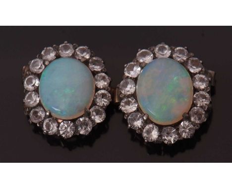 A pair of opal and white stone jewels, the oval opal cabochons, surrounded by white hardstones, each set in unmarked yellow m
