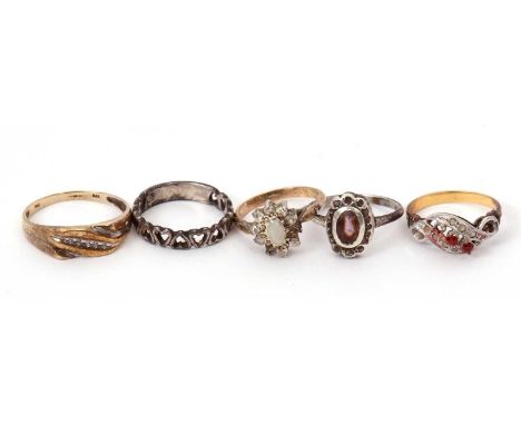 A 9ct diamond ring and four other rings: the 9ct ring set with five diamond highlights, with tapered shoulders and plain band