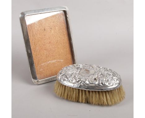 A silver photo frame with engraving to top and bottom, assayed for Birmingham, 1917, together with a silver topped brush with