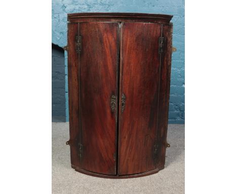 A Georgian mahogany four shelf convex/bow fronted corner cabinet. Height: 101cm, Width: 66cm, Depth: 46cm.  In need of restor