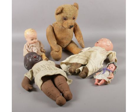 A vintage jointed teddy bear along with four vintage dolls.  