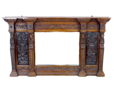 A carved oak overmantel mirror, the bevelled rectangular plate flanked by carved panels and four bust topped pilasters, below