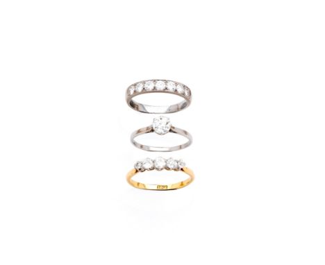 THREE DIAMOND RINGS comprising: circular diamond in a claw setting between tapering shoulders; half eternity ring set with se