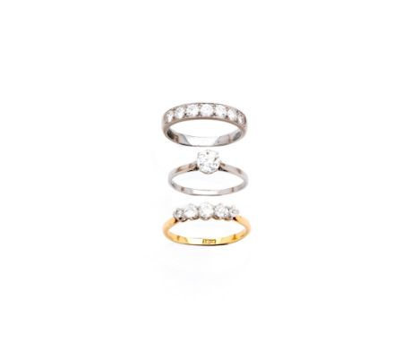 THREE DIAMOND RINGS comprising: circular diamond in a claw setting between tapering shoulders; half eternity ring set with se