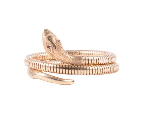 A 9 carat yellow gold articulated snake bangle, engraved head with ruby set eyes, coiled articulated body with engraved tail,