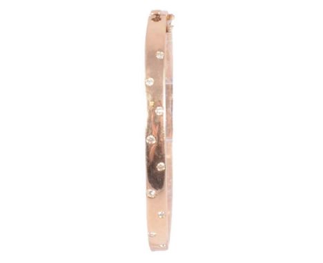 A diamond set yellow metal half-hinged bangle, 5.5mm wide hollow bangle with nine brilliant cut stones collet set to the fron