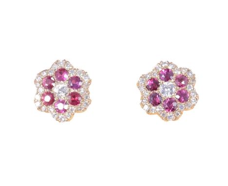 A pair of ruby and diamond earstuds, each with a central brilliant cut diamond surrounded by six brilliant cut rubies, with a