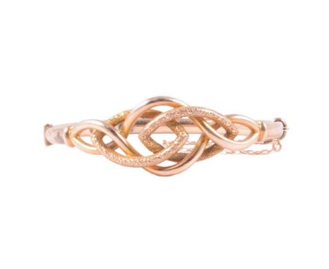 A yellow metal half hinged bangle, hollow construction with a plain and stippled finish knot to front, 9c pad stamp, 8.4g.Con
