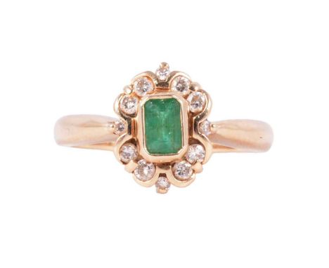 An emerald and diamond cluster ring, the rectangular step cut emerald collet set and surrounded by twelve brilliant cut diamo