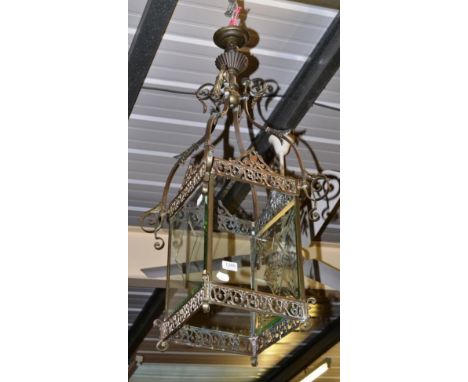 A patinated metal four-sided ceiling lantern with leaf and scroll arms 