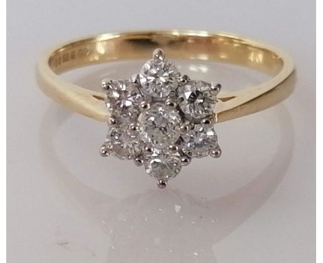 A diamond cluster ring on an 18ct gold setting, the central brilliant-cut diamond approximately 0.15 carats, surrounded by fi