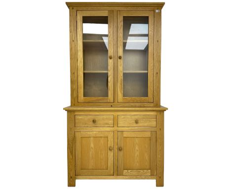 Contemporary light oak bookcase display cabinet, fitted with  two glazed doors enclosing two shelves, above two drawers and c