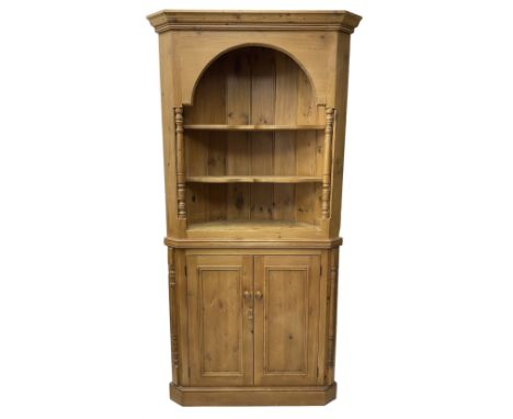 Waxed pine floor standing corner cupboard, projecting cornice over two open shelves flanked by turned uprights, base fitted w
