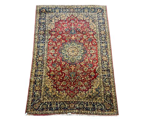 Persian Kashan red ground carpet, the field decorated with central medallion surrounded by trailing branches and stylised pla