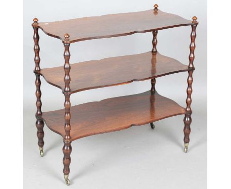 A Victorian rosewood three-tier whatnot, raised on bobbin turned supports and castors, height 75cm, width 76cm, depth 37cm.